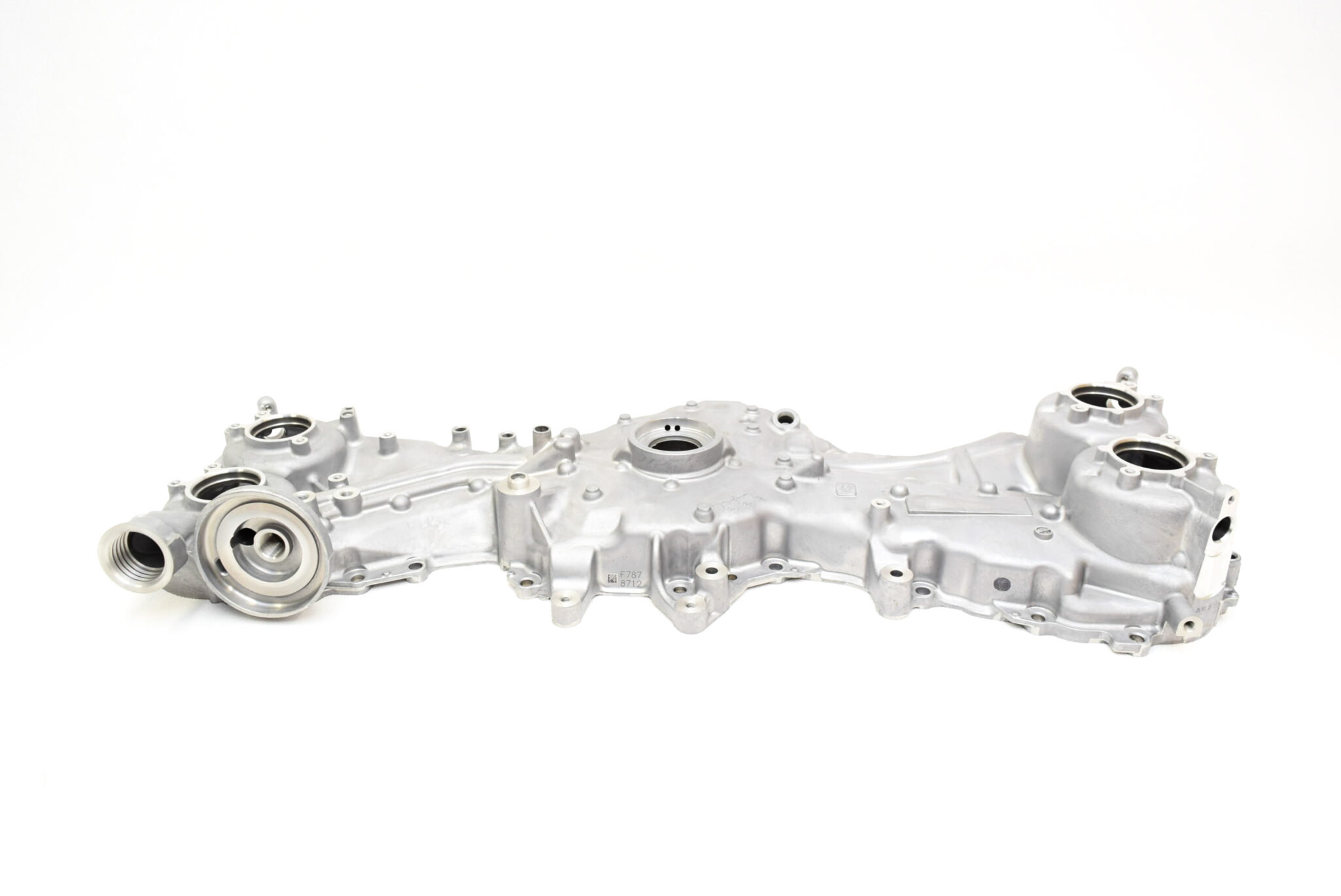 Silver automotive engine housing laid on a white background, showing circular ports and bolt holes across its perimeter.